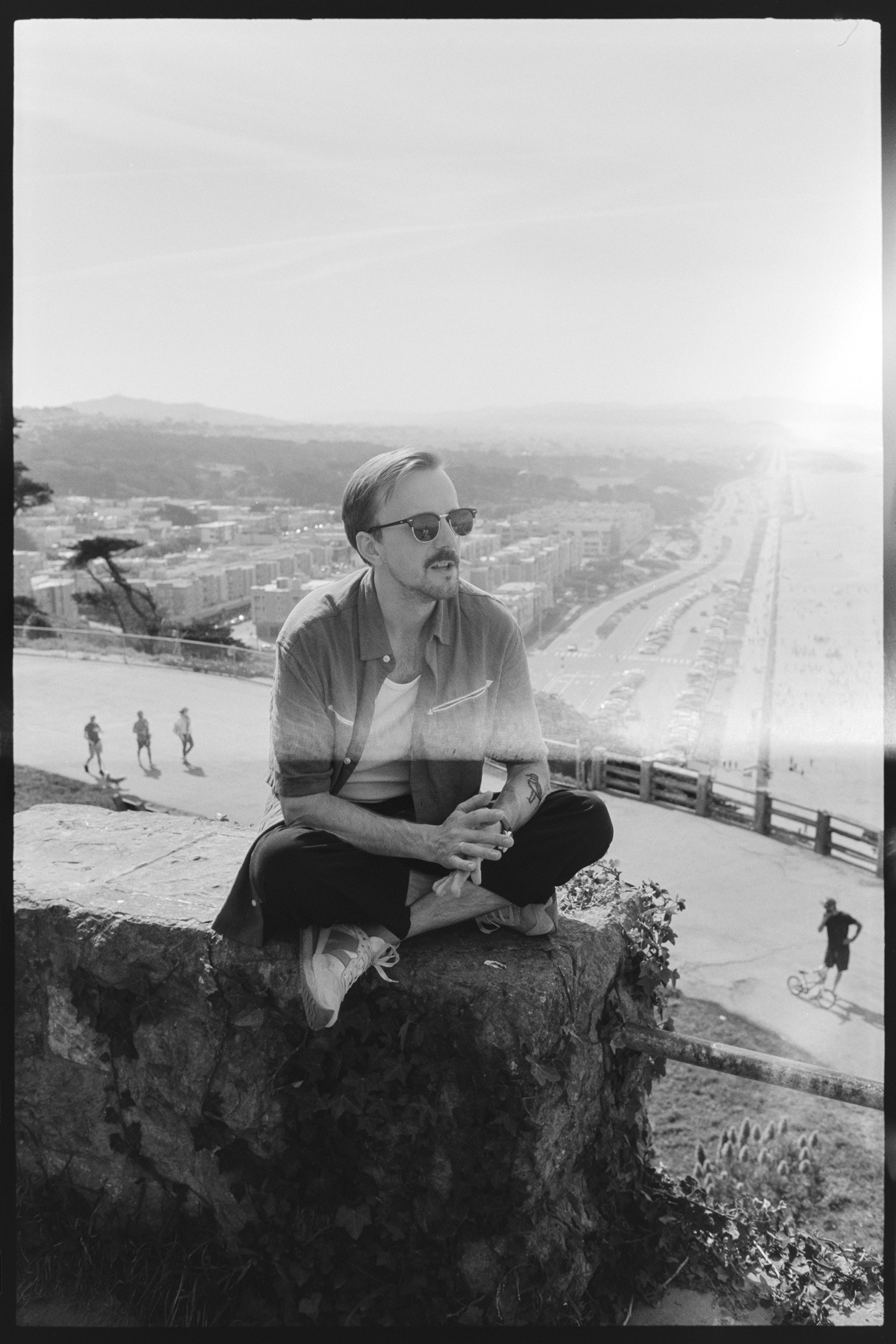 A man in sunglasses sitting on a rock overlooking the Pacific coast at Sutro Heights in San Francisco