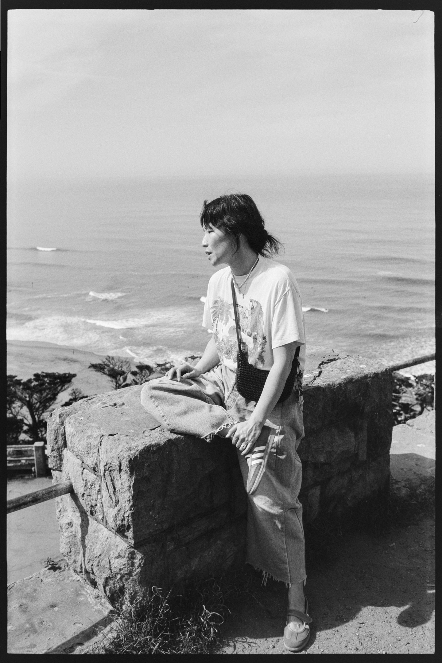A woman sitting on a rock overlooking the Pacific coast at Sutro Heights in San Francisco