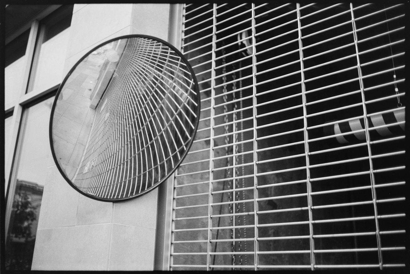 A circular convex mirror mounted next to a parking garage door in San Francisco