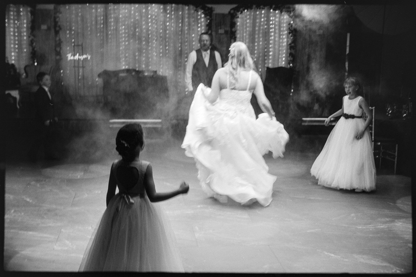 A newlywed couple dancing at their wedding receptive with three kids surrounding them