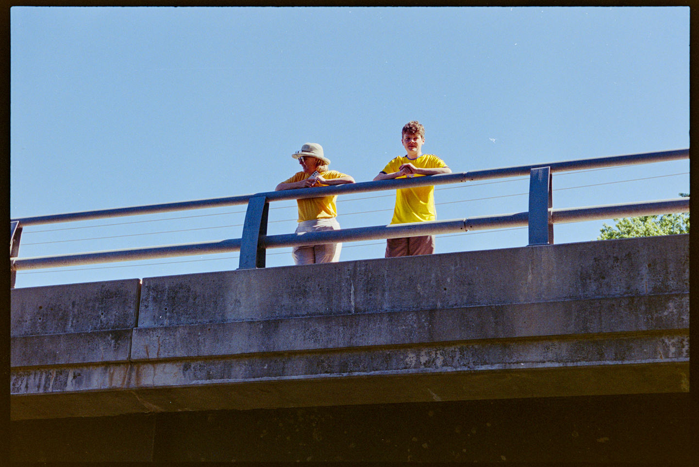 Two people look below from the bridge at the group of kayakers