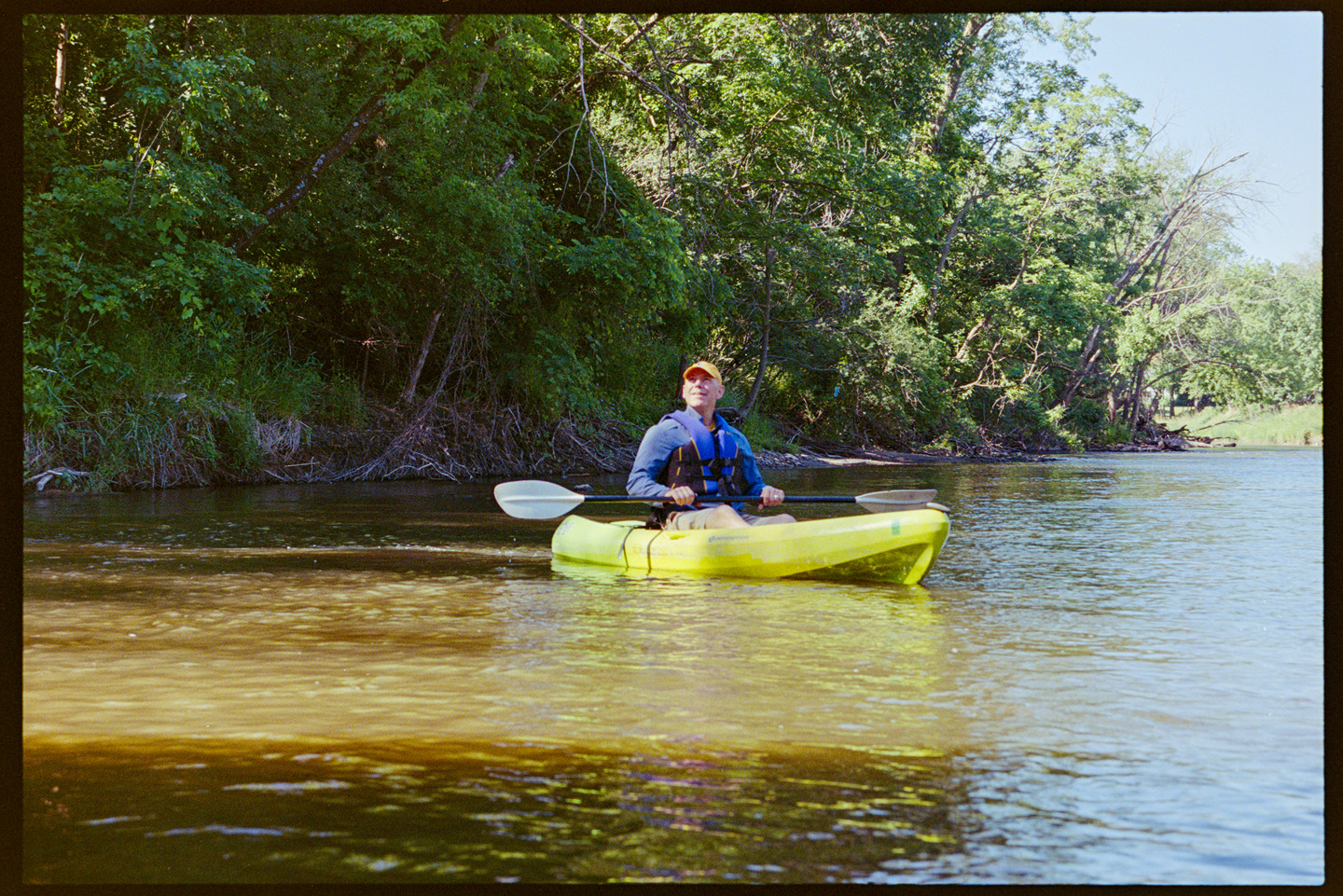 A man look up from his kayak on the river into the sunshine