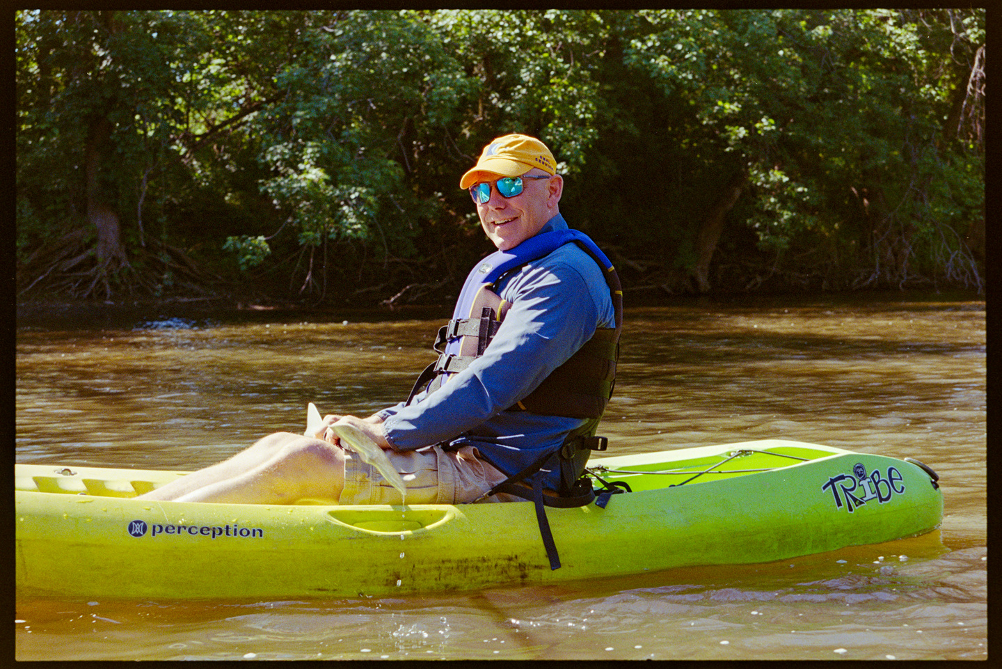 A man smiles at the camera from his kayak on the river