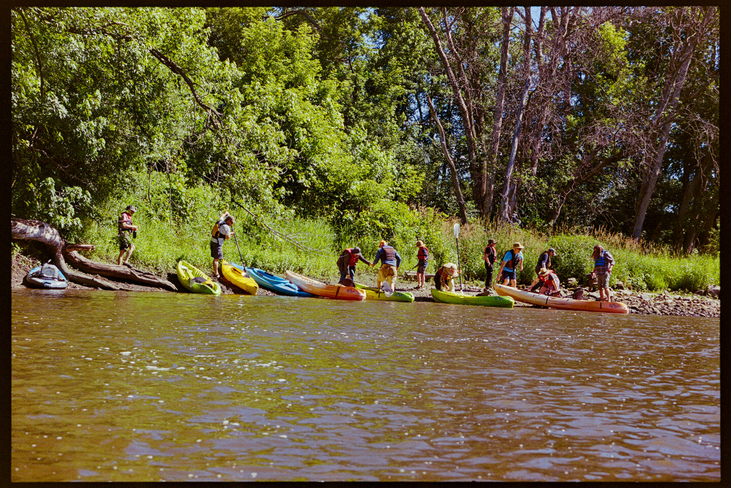 A group of kayakers have stopped on a beach for a rest